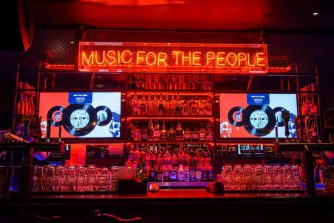 Über einem Tresen in einer Bar hängt die Leuchtschrift: Music for the People
