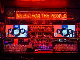 Über einem Tresen in einer Bar hängt die Leuchtschrift: Music for the People